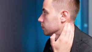 Man touching the area behind his ear, representing ear cleaning tool safety